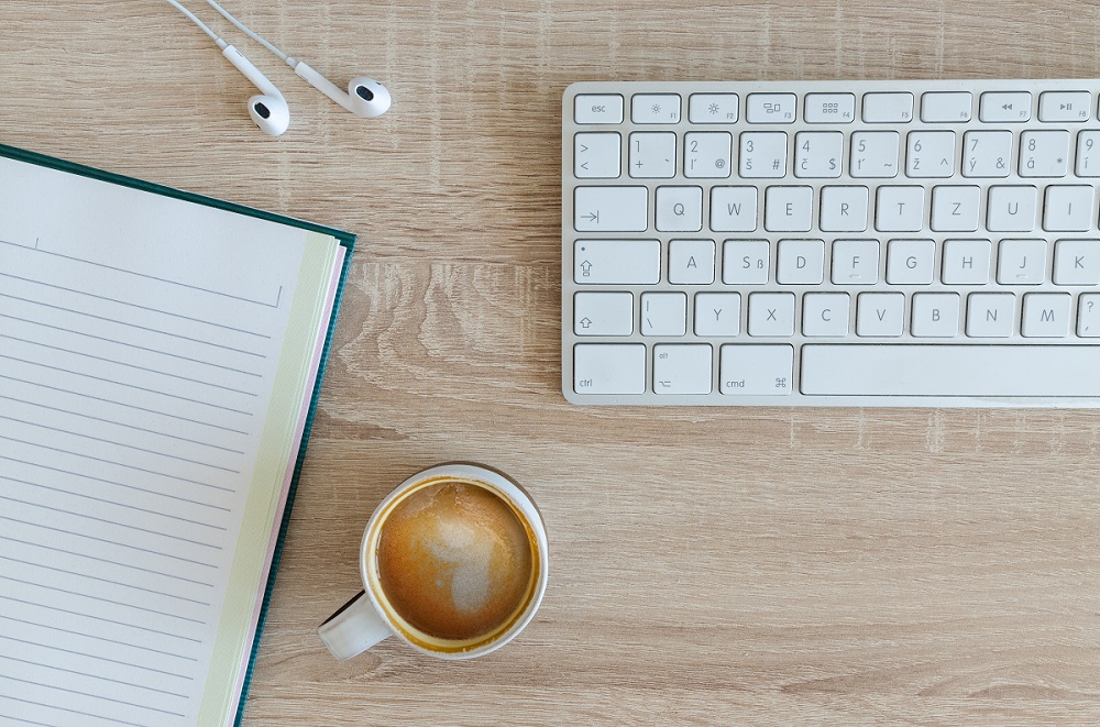 Featured Image Option 2 with a mac keyboard, earpods, a notebook, and coffee.